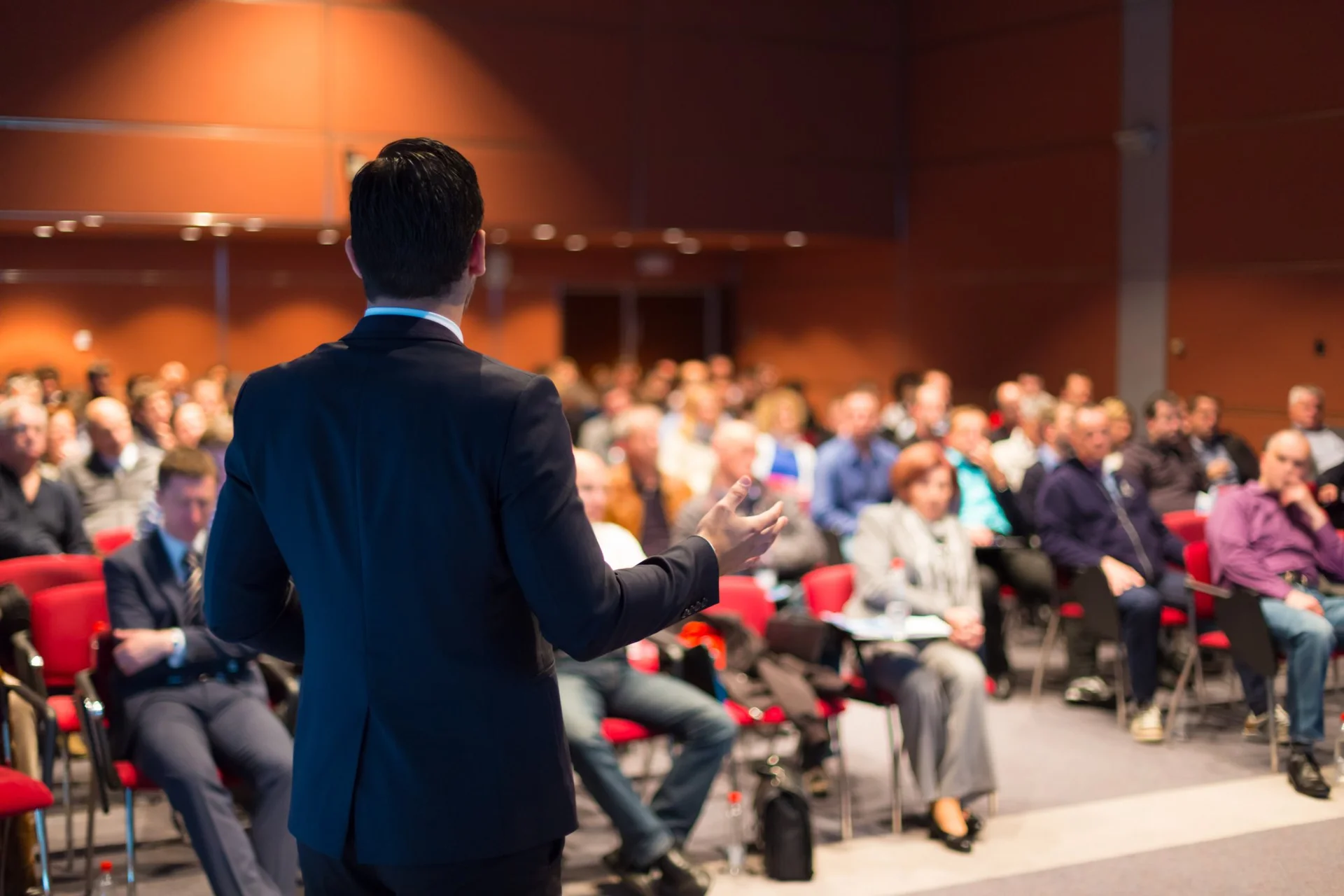 Professional speaker delivering a keynote presentation on stage to a large conference audience