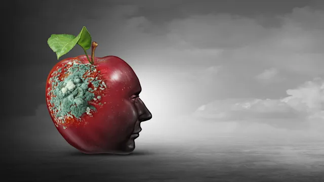 a human face in a red apple stares into the distance. Rot creeps across the back of the apple's head