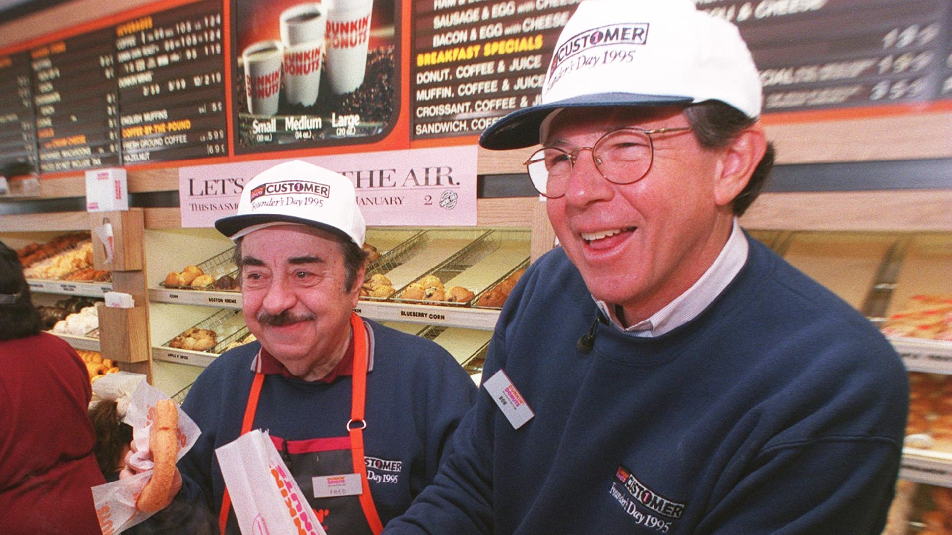 Dunkin' Donuts CEO Bob Rosenberg pours a customer coffee as actor Michael Vale, who plays "Fred the Baker" in TV commercials, gets ready with a donut at the original Dunkin' Donuts location in Quincy, Massachusetts on January 31, 1995.