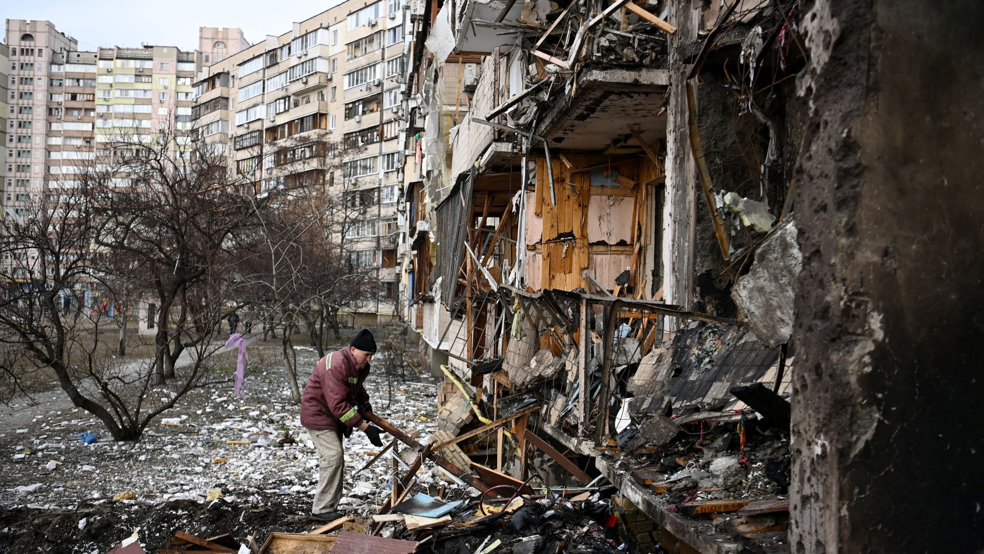 A man clears debris at a damaged residential building at Koshytsa Street, in a suburb of the Ukrainian capital, Kyiv.