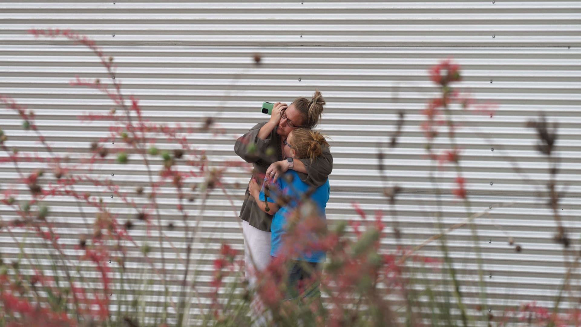 On May 24, a woman in Uvalde, Texas, cries and hugs a young girl while on the phone outside the Willie de Leon Civic Center where grief counseling will be offered.